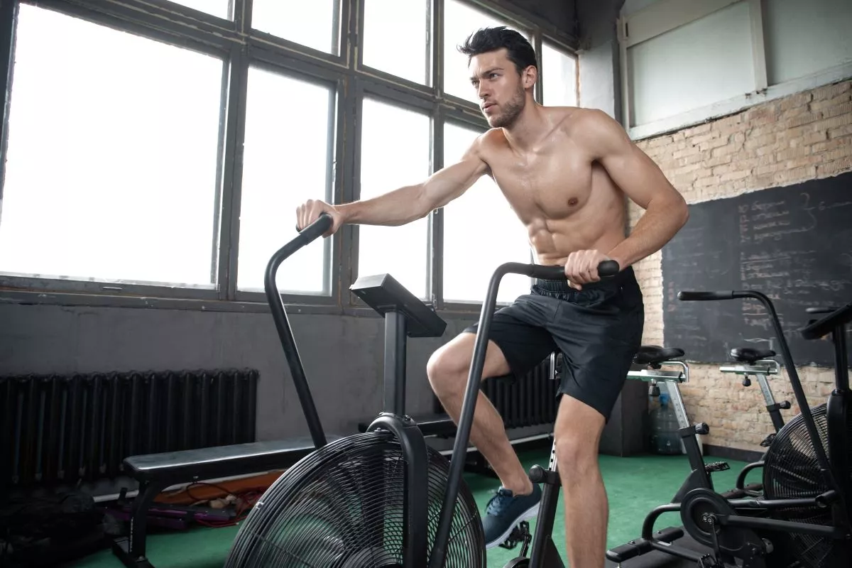 Férfi airbike szobakerékpáron végez kardióedzést az edzőteremben