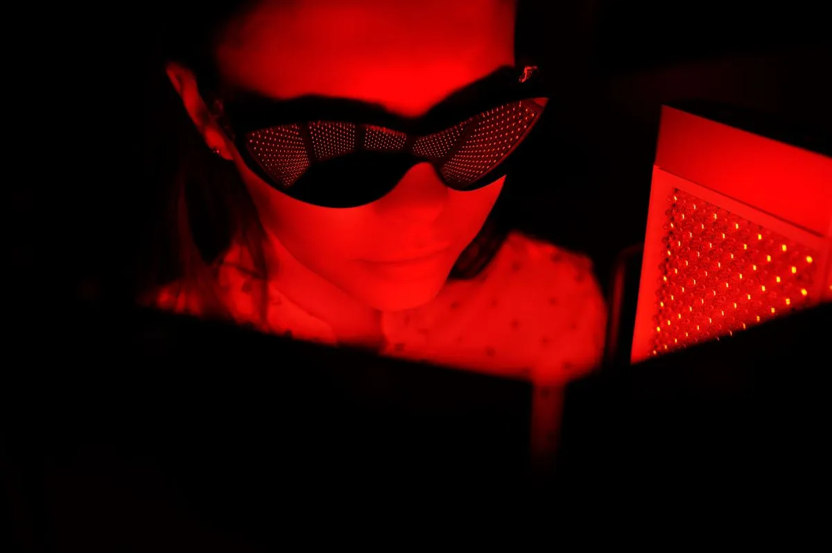 Nő védőszemüvegben vörös fényes LED panel előtt pihen